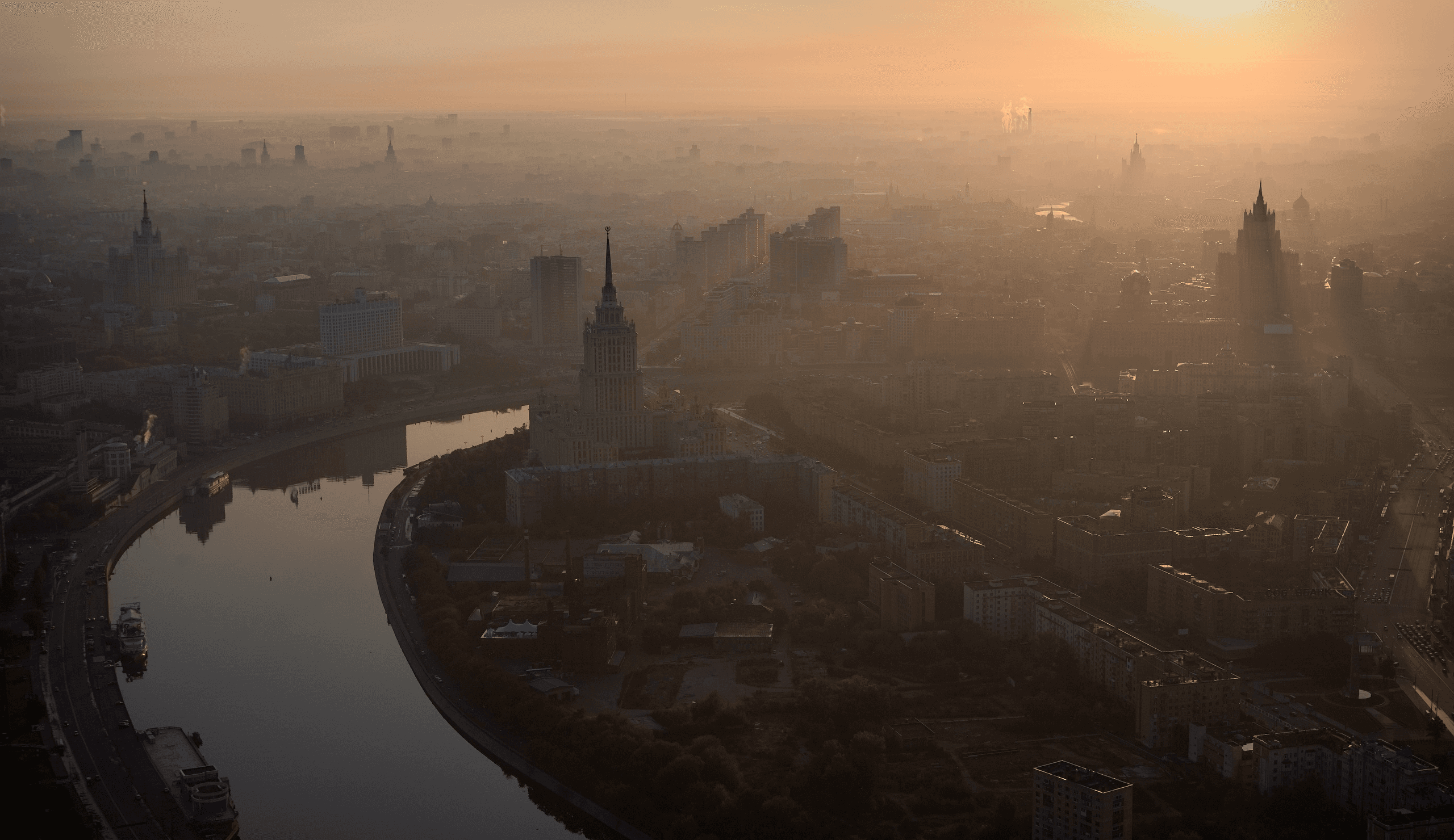 Пустая улица спального района на рассвете: туман, ещё горят фонари, в окнах начинает загораться свет